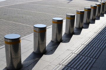 A row of pillars along the road for the safe passage of pedestrians along the sidewalk. - obrazy, fototapety, plakaty