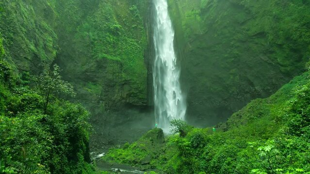 Beautiful rain forest foggy waterfall. Kabut Pelangi air terjun in Lumajang, East Java Timur. Aerial dramatic drone view.