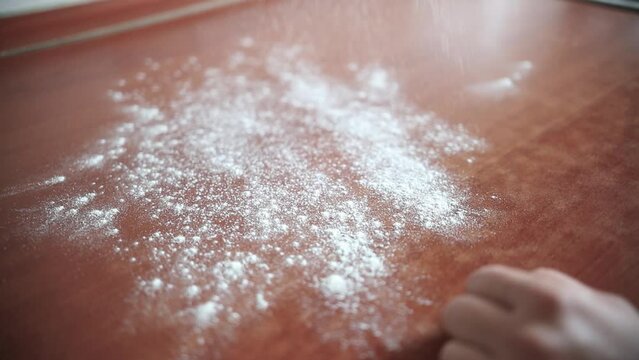 Slow motion footage of a person throwing flour onto the table