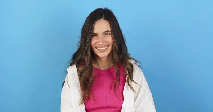 Amazed excited woman hairstyle in white shirt, pink top open mouth in surprise looking at camera with big eyes, shocked. Indoor studio shot isolated on blue background. Oh my god wow, yes gesture.