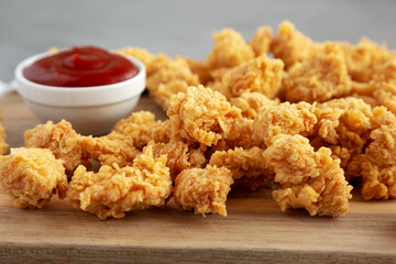 Homemade Crunchy Popcorn Chicken with Ketchup on a Board, side view.