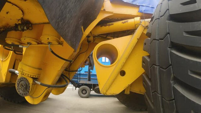 A man walks under the world's largest quarry truck. Large truck wheels, frame and suspension components. First person view. Cargo tyres of a quarry truck. POV