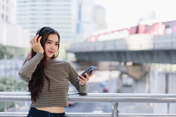 Beautiful Asian woman traveler relaxes while listening to music Young Asian tourist waits for...