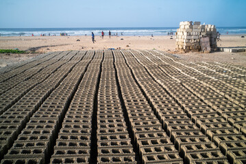 des moellons en fabrication sèchent sur le rivage  d'une plage dans un quartier populaire de Dakar au Sénégal en Afrique - obrazy, fototapety, plakaty