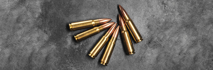Bullets for Kalashnikov assault rifle on gray concrete and gradient black background banner....