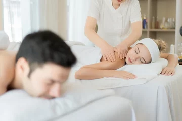 Foto op Canvas Happy young beautiful couple enjoying back and shoulder massage at the spa. Relaxed Husband And Wife at Asian luxury spa and wellness center © Exnoi