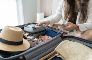 Woman packing suitcase on bed for a new journey packing list for travel planning preparing vacation...