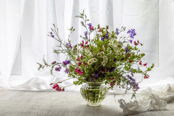 Still life with a bouquet of wild flowers on the windowsill on a sunny day - obrazy, fototapety, plakaty