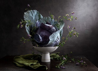 Modern still life with red cabbage and small flowers in a vase on a wooden table