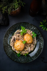 Dinner chicken meatballs with barley porridge, mushrooms, sauce and herbs on dark background.