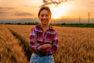 The Chinese farmer woman strikes a pose for a photo in the wheat field, radiating confidence and pride in her agricultural endeavors. © DusanJelicic