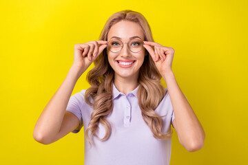 Portrait of cheerful clever nice girl toothy smile hands touch glasses isolated on yellow color background