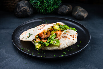 Snack flatbread with stuffing, chicken, beef, lettuce, arugula, onions and sauce in a plate.