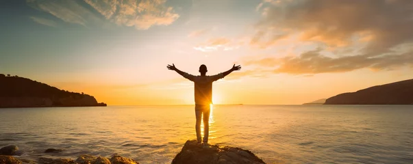 Selbstklebende Fototapete Dämmerung Young man arms outstretched by the sea at sunrise enjoying freedom and life, people travel wellbeing concept
