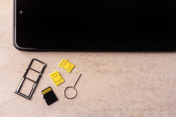 smartphone and open slots for nano SIM cards, two nano SIM cards, micro SD drive and metal key on grey background