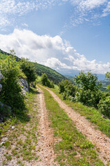 Fototapeta na wymiar Unpaved road through the hilly landscape of the Croatian Mountains.