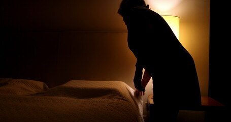 Older woman prepares to go to bed and sleep. Person lays down in bed and turns off night stand...