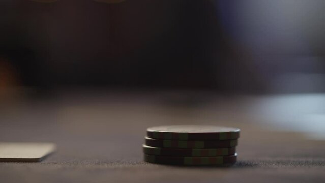 Close-up of the poker player's hand moving the chips on the cloth. The moment of the bet selection