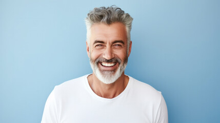 Portrait of handsome bearded elderly man keeps self confident cheerful expression at camera wears formal shirt and spectacles for vision correction isolated on blue wall - obrazy, fototapety, plakaty