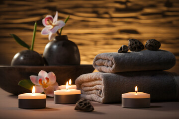 Burning candles, stones and towel on massage table in spa salon Generative AI