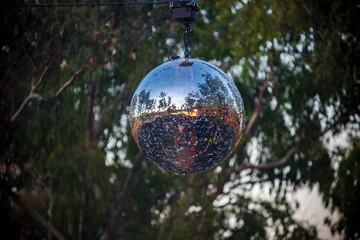 View of a disco ball hanging on a festival stage located in a forest