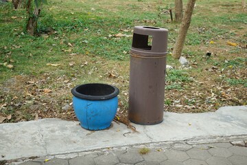 two trash cans made of rubber and metal in a city park