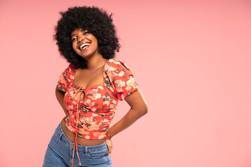 Charming girl looking and smiling to the camera, posing in jeans and fashionable top. Attractive laughing african woman.