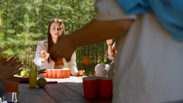 Young woman playing beer pong. Stock footage. Beautiful woman throws ball into glass of beer. Fun game for friends with alcohol and ping pong in nature in summer