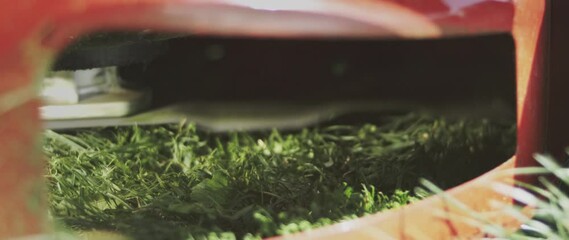 Extreme close-up view of lawn mower blades spinning on the ground and cutting extra grass in the yard. Shot in slow-motion