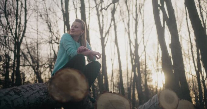 Female explorer crouching on logs in forest