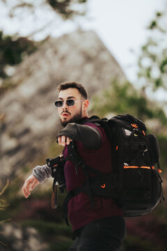 Fot&oacute;grafo con mochila haciendo gesto con los brazos en los Alpes