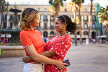 Lesbian couple embracing in a square downtown