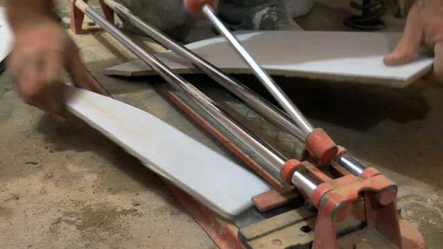 Footage of a bathroom reconstruction and a utility man cutting a ceramic tile with a tile cutter