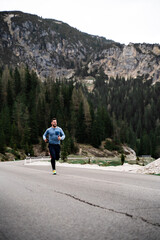 Chico haciendo deporte en Dolomitas , con las montañas y arboles al fondo. 