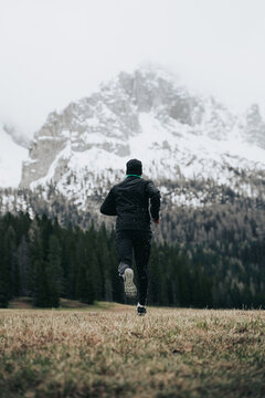 Chico corriendo hacia una monta&ntilde;a nevada en Dolomitas Alpes Italianos. 