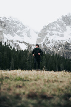 Hombre corriendo en llano con monta&ntilde;a nevada de fondo en Dolomitas.