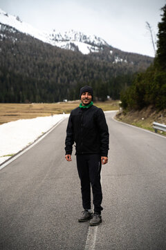 Hombre con gorro  en una carretera en Dolomitas con  monta&ntilde;as con nieve . 