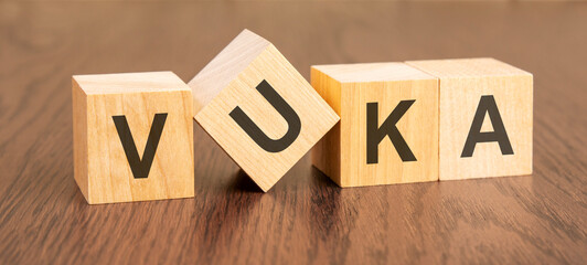 wooden blocks with word VUKA on dark wooden background. Volatility Uncertainty Complexity Ambiguity...