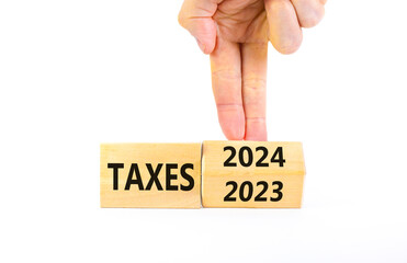 2024 taxes new year symbol. Businessman turns a wooden cube and changes words Taxes 2023 to Taxes...