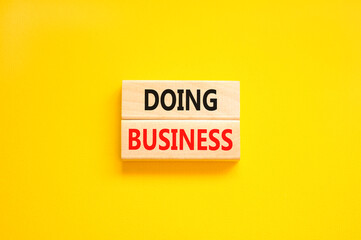 Doing business symbol. Concept words Doing business on beautiful wooden block. Beautiful yellow table yellow background. Business, motivational Doing business concept. Copy space.