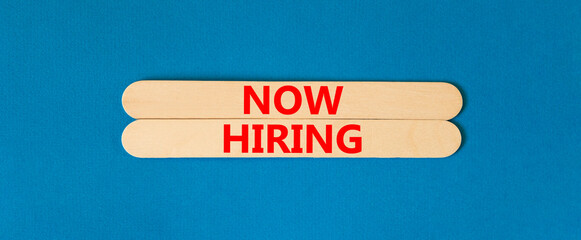 Now hiring symbol. Concept words Now hiring on wooden stick. Beautiful blue table blue background. Business marketing, motivational now hiring concept. Copy space.