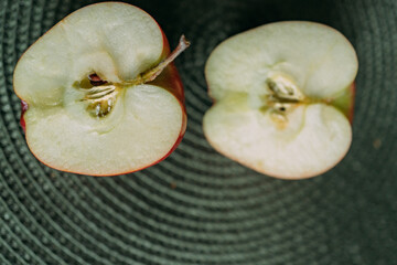 Two red ripe apples on a green napkin. The apple is cut in half. Two halves of an apple