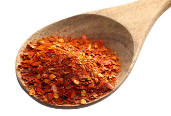 Spicy chili pepper flakes, crushed in wooden spoon, milled dry paprika pile isolated on white
