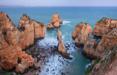 Long exposure image of the rocky Algarve coast with steep cliffs in the vicinity of the village of Lagos, Portugal in the blue hour after sunset
 - obrazy, fototapety, plakaty
