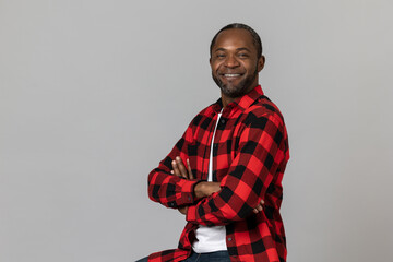 Confident happy black bearded man with folded hands wearing red checkered shirt