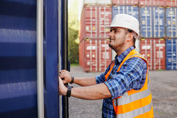 Young man container worker wearing white helmet opening containers checking goods at a port warehouse. Import and export shipping.