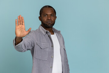 Serious black man wearing gray shirt showing stop sign