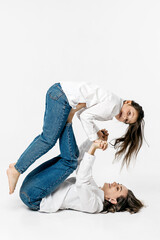 Young mother and little girl playing on a white background. The concept of advertising positive, happy sincere emotions, clothes and a happy carefree life.
