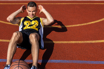 Obraz premium Handsome man doing abs training on basketball court.