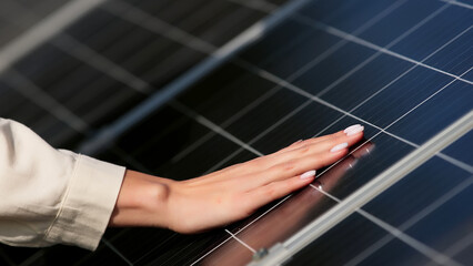 Close-up of a young female engineer checking the operation of the sun and the cleanliness of photovoltaic solar panels. Concept renewable energy, technology, electricity, services, green